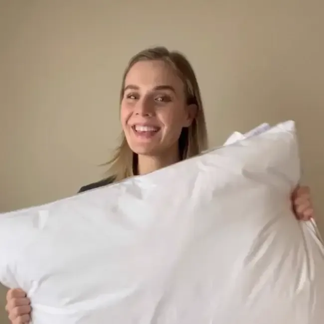 Smiling woman hugging a white pillow