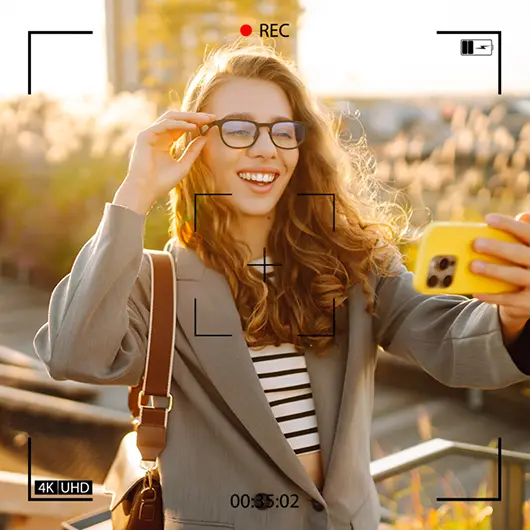Woman taking a photo with her phone while wearing smart glasses