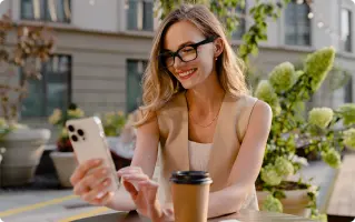 Woman with coffee and phone outdoors