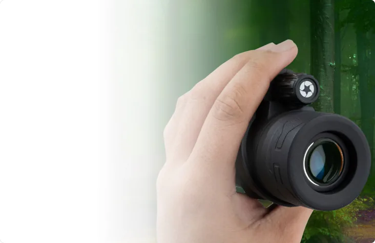 Hand holding the monocular with a forest in the background